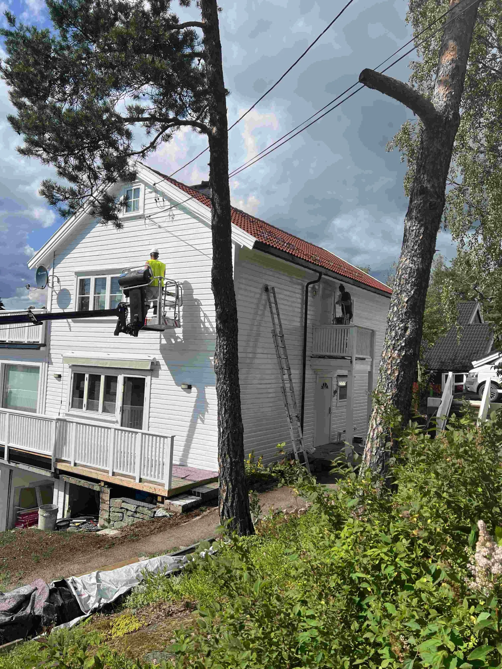 Utvendig maling av trehus fra lift